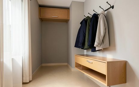 Mały przedpokój w bloku z płytką szafką na buty, wieszakiem na kurtki i szafką nad drzwiami